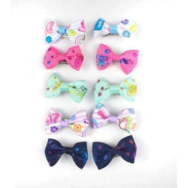 Imagen que muestra el producto Clip De Moño Pinzas Para Mascotas. Set de moños en pinza para mascotas. Material: Poliéster, metal Color: Disponible en la foto Disponible: Razas pequeñas y medianas.