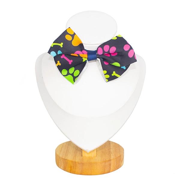 Imagen que muestra el producto Collar Con Moño Estampado. Collar con moño estampado, cuenta con hebilla ajustable y broche de seguridad. Material: Poliéster Color: Rosa mariposa, azul oscuro huellas, rosado con azul rayas, lila flores, rojo estilo tartán, blanco corazones y perritos. Disponible: Razas pequeñas