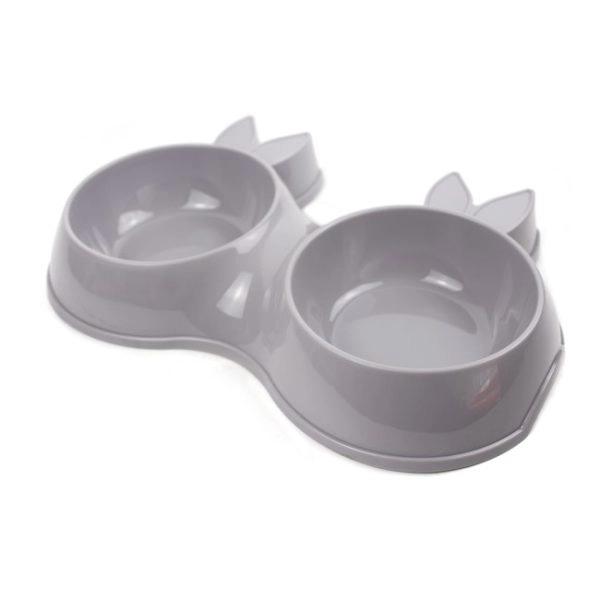 Imagen que muestra el producto Comedero Mascotas Con Bowl Removible. Comedero doble para mascotas, cuenta con bowl removibles. Material: Plástico Color: Gris, rosado Disponible: Razas pequeñas.